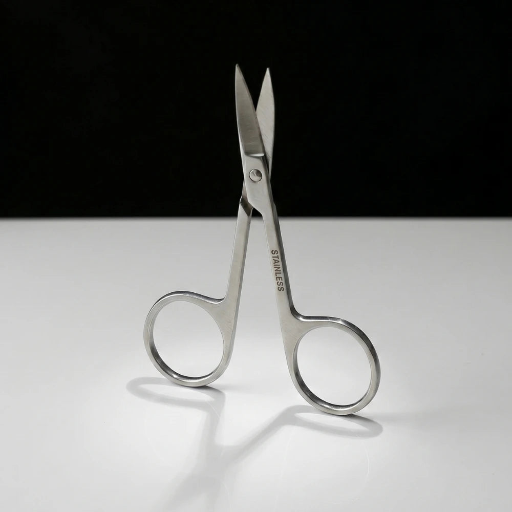 Pair of silver scissors on a white surface with a black background